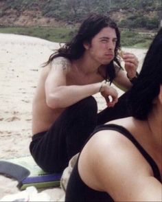 a man sitting on top of a beach next to a woman