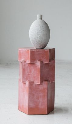 a white vase sitting on top of a pink block