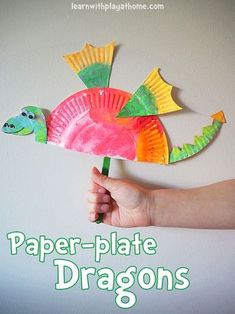 a hand holding a paper plate dragon on top of a white wall with text overlay