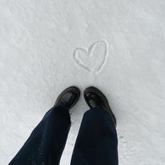 someone is standing in the snow with their feet up and heart drawn on the snow