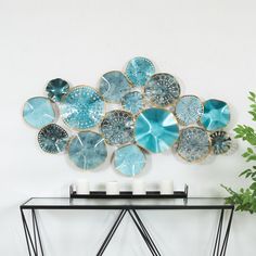 a glass table topped with blue plates and candles next to a vase filled with flowers