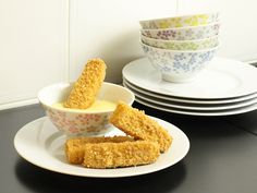 several plates stacked on top of each other with dipping sauce in them and fried fish sticks sticking out of the middle