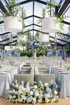 an indoor dining area with blue and white flowers on the tables, chandeliers and chairs