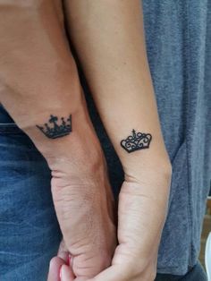 two people holding hands with tattoos on their arms and one has a crown tattooed on the wrist