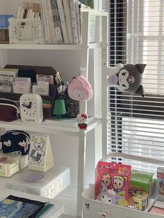 a white shelf filled with lots of items next to a window