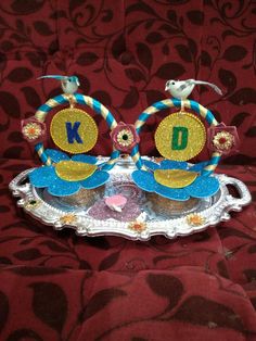 two decorated cupcakes sitting on top of a silver tray with letters k and d