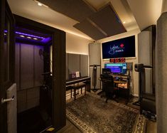 a recording studio with several monitors and sound equipment on the wall, along with an area rug