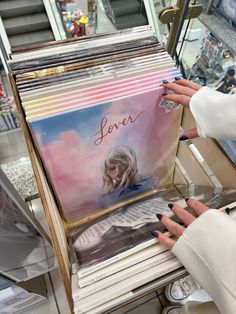 a woman holding up a stack of cds in front of a store window with the words love on it