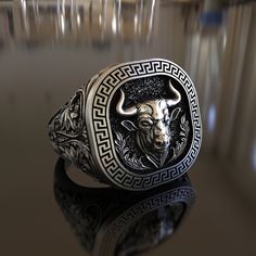 Introducing our meticulously handcrafted Bull Ring Greek Ornament Themed 925 Sterling Silver Ring. This unique piece of jewelry is a tribute to the rich mythology and art of ancient Greece, making it an ideal gift for history lovers, art enthusiasts, or anyone who appreciates unique designs. The ring is made from 925 sterling silver, known for its durability and timeless appeal. It features a detailed bull and Greek ornament, symbols of strength and beauty, making it a conversation starter where Symbolic Carved Sterling Silver Rings, Artisan Carved Sterling Silver Jewelry, Ceremonial Sterling Silver Rings With Polished Finish, Sterling Silver Rings With Polished Finish For Ceremonial Occasions, Sterling Silver Rings With Polished Finish For Ceremonies, Silver Oxidized Finish Signet Ring As Gift, Symbolic Carved White Gold Jewelry, Carved White Gold Sterling Silver Jewelry, Symbolic Carved Sterling Silver Signet Ring