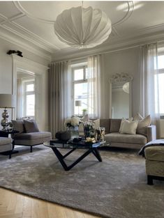 a living room filled with lots of furniture next to two windows and a chandelier