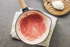 a pan filled with food sitting on top of a table next to a wooden spoon