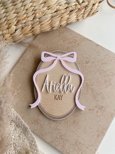 a wooden plaque with the name ariella kay on it sitting next to a basket