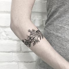 a woman's arm with a tattoo on it that has flowers and leaves on it