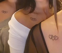 two women with matching tattoos on their chests, one is holding her arm around the other