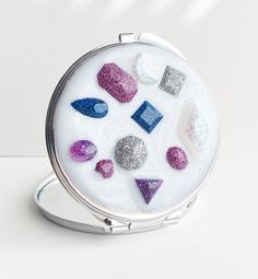 a compact purse with glittered rocks and stones in it on a white table top