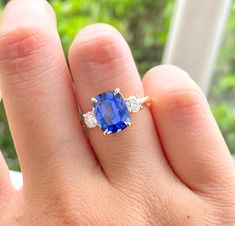 a woman's hand with a ring on it and a blue stone in the middle