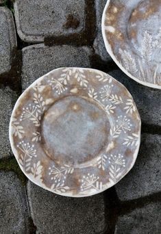 two white plates sitting on top of a stone floor