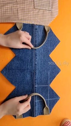 someone is cutting out the fabric on top of a piece of blue jeans with scissors