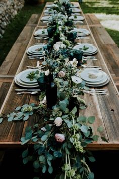 a long wooden table topped with plates and flowers