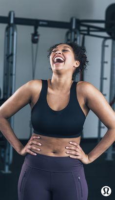 a woman laughing in the gym with her hands on her hips