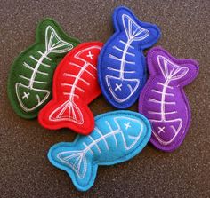 four different colored fish shaped patches sitting on top of a table next to each other