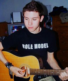 a young man is playing an acoustic guitar