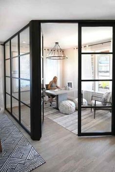 a woman sitting at a desk in front of a glass walled room with sliding doors