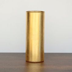 a gold vase sitting on top of a wooden table