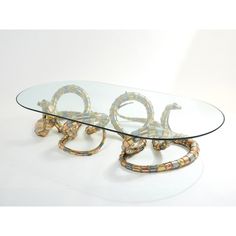 a glass table with two snakes on it's legs and an oval glass top