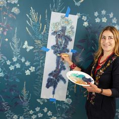 a woman holding a plate and painting on a wall