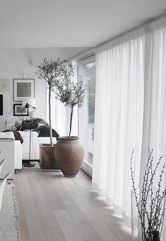 a living room filled with white furniture and large vases on top of wooden floors