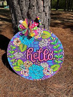 a sign that says hello on it next to a tree