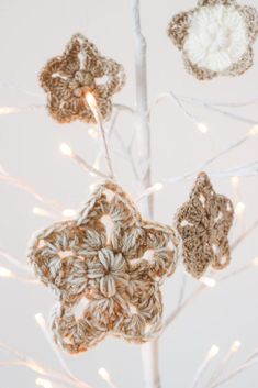 crocheted ornaments are hanging from a tree with white lights in the background,