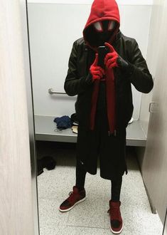 a man in a black jacket and red hoodie taking a selfie