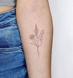 a woman's arm with a small flower tattoo on the left side of her arm