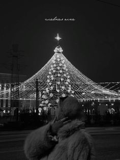 a person standing in front of a lit up christmas tree