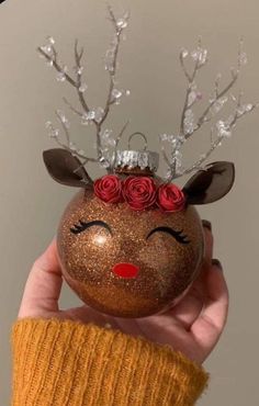 a hand holding up a christmas ornament with flowers on it's head