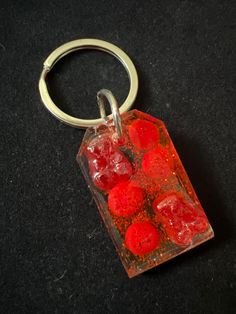 a keychain with red gummy bears in it sitting on a black surface