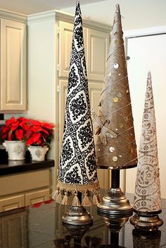 three small christmas trees on top of a table in front of a white kitchen counter