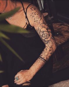 a woman with a tattoo on her arm and leg, sitting at a wooden table