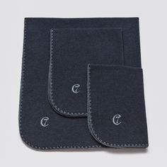 two pieces of black wool with white stitching on the side and one piece of grey fabric