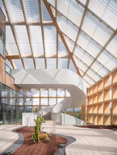 the inside of a building with a spiral staircase and cactus in the ground below it