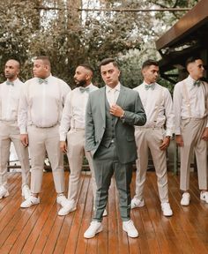 a group of men standing next to each other on a wooden floor in front of trees