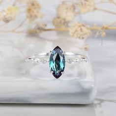 a white gold ring with an oval cut blue topazte surrounded by small diamonds