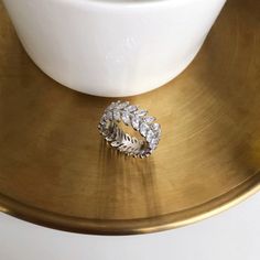 a gold plate with a ring on top of it and a white bowl in the background