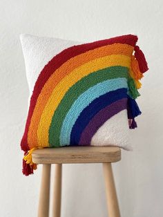 a multicolored pillow sitting on top of a wooden stool