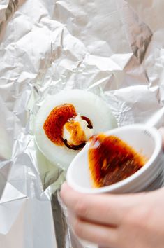 someone is dipping sauce on top of an egg in a white bowl with red stuff