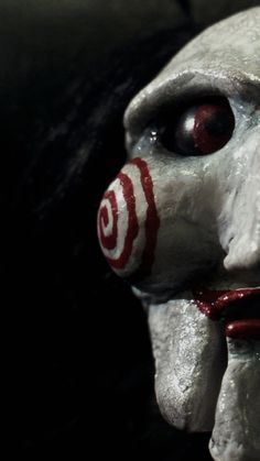 a creepy clown mask with red eyes and nose paint on it's face is seen in this image