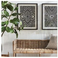 two black and white paintings on the wall above a wicker bench