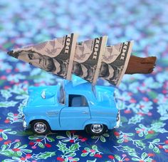 a blue toy truck with money sticking out of it's roof on top of a table